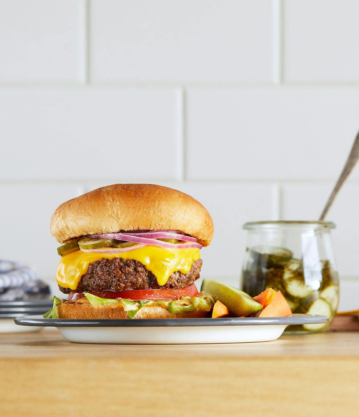 Cheeseburger next to pickles.