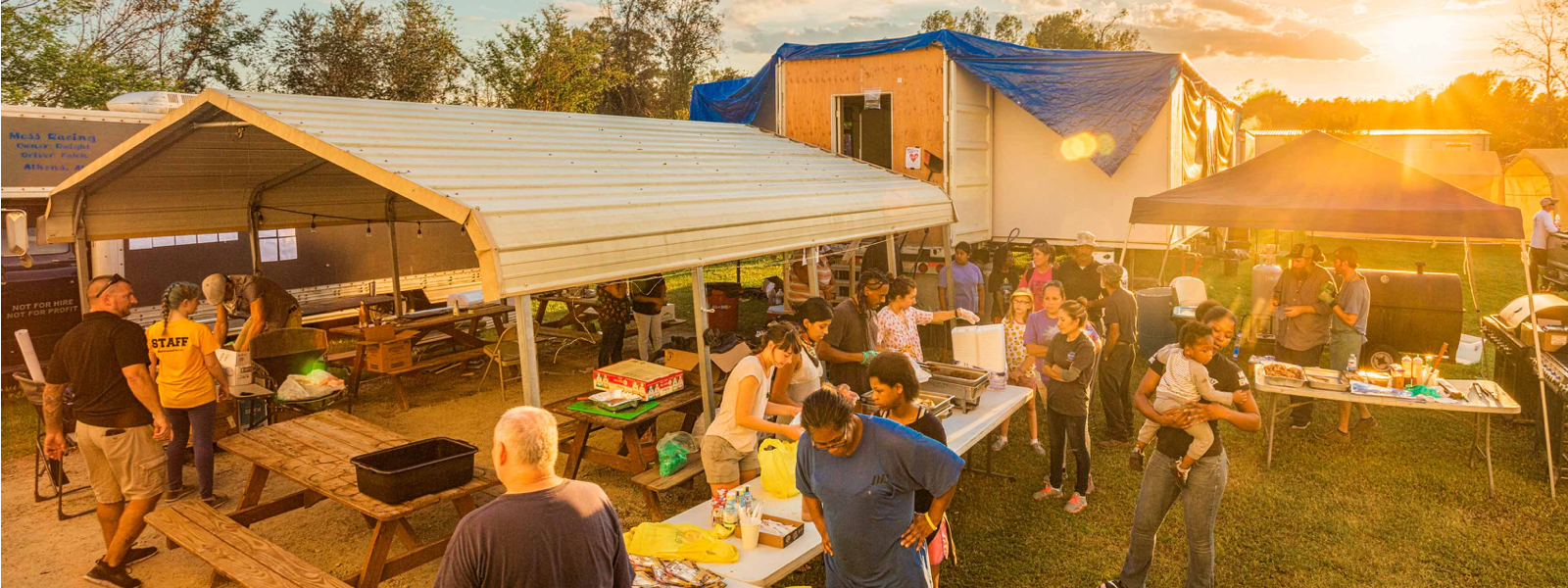 People pick up supplies from a disaster relief station at sunset.