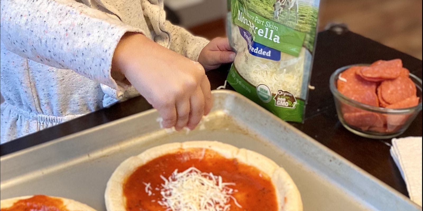 Young child sprinkles organic cheese on their mini pizza. Photos contributed by Jackie Thesing.