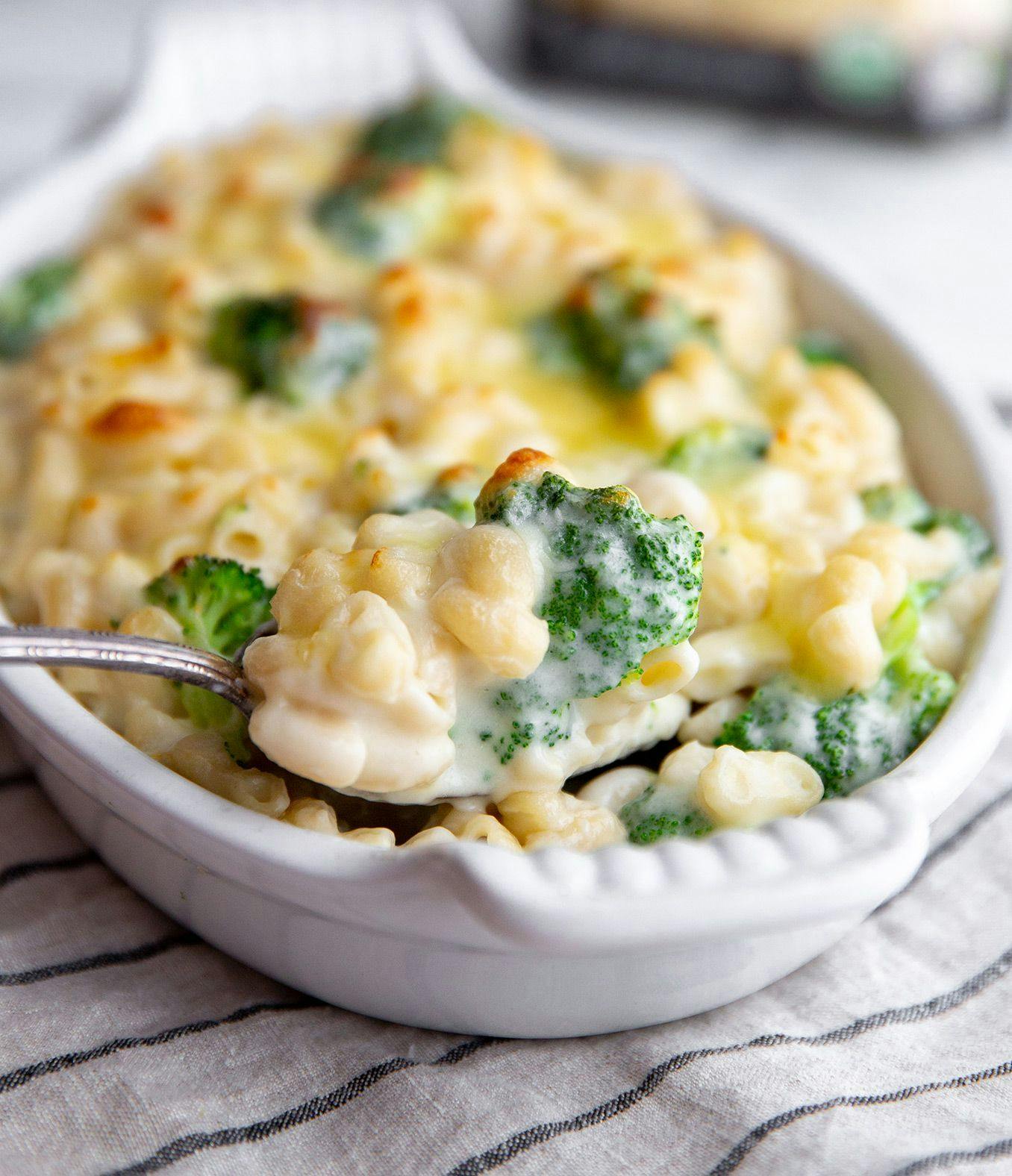 A bowl of creamy mac and cheese with broccoli and a spoon in the bowl.