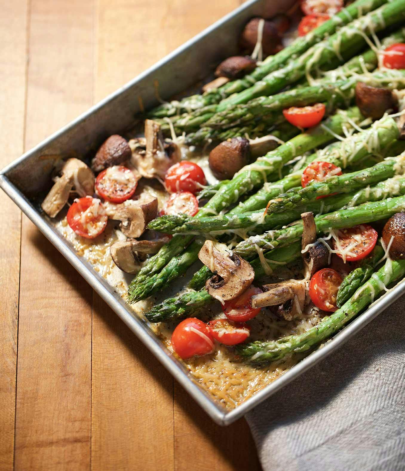 Butter-Roasted Asparagus on a baking sheet with cherry tomatoes and mushrooms.