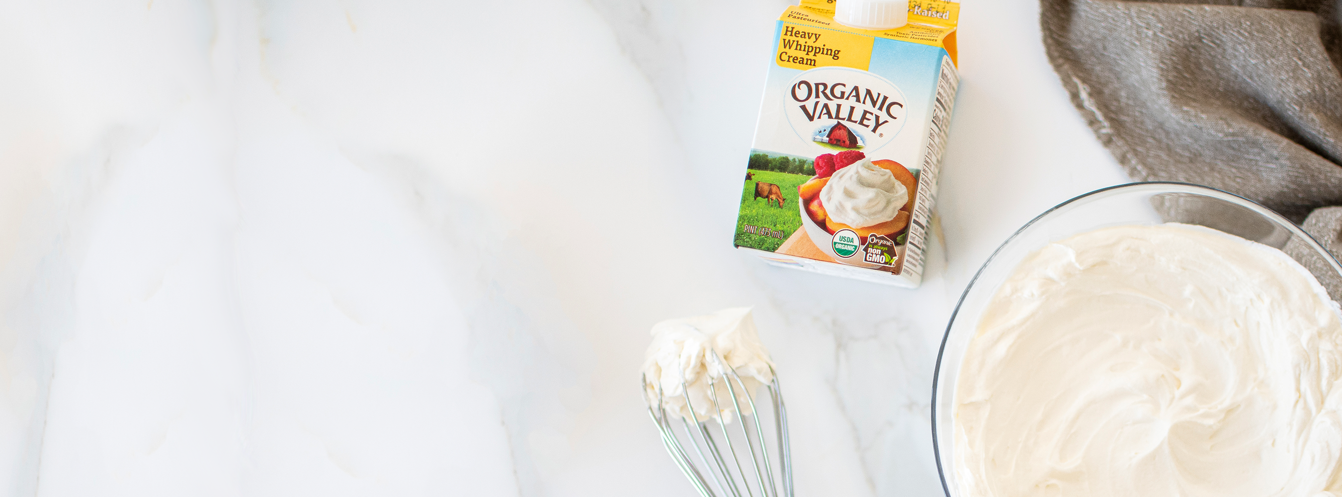 A bowl of Organic Valley Heavy Whipping Cream and a whisk. 