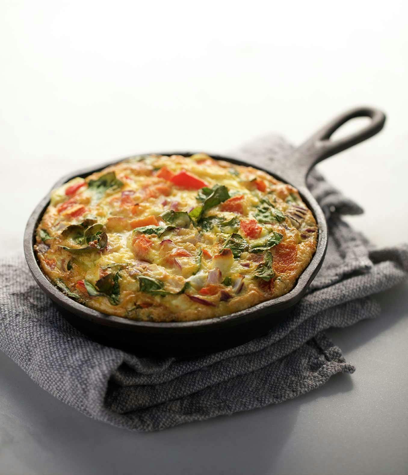 An Organic Mama Veggie Frittata in a skittle on top of a kitchen towel.