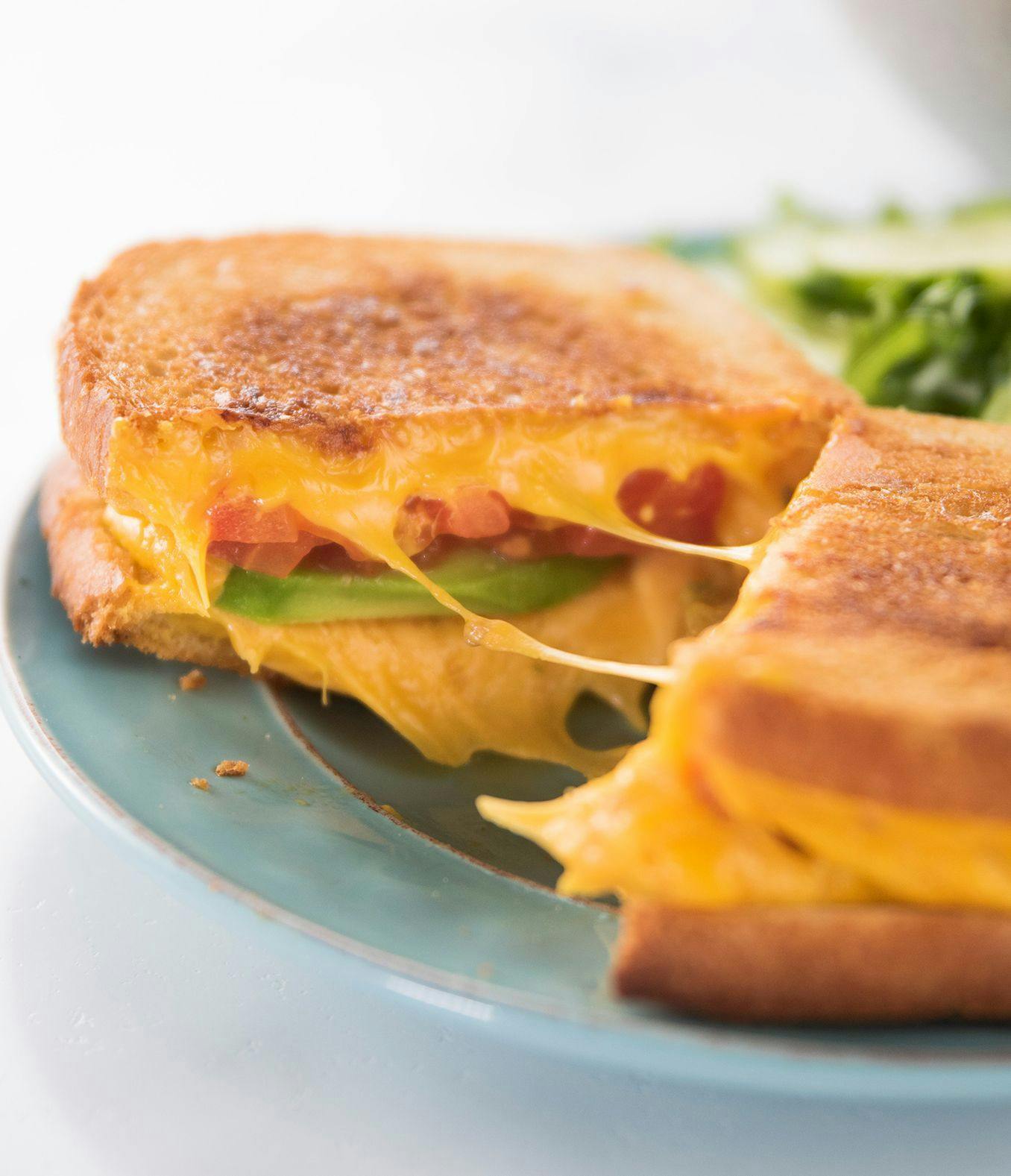 An avocado grilled cheese cut in half. 