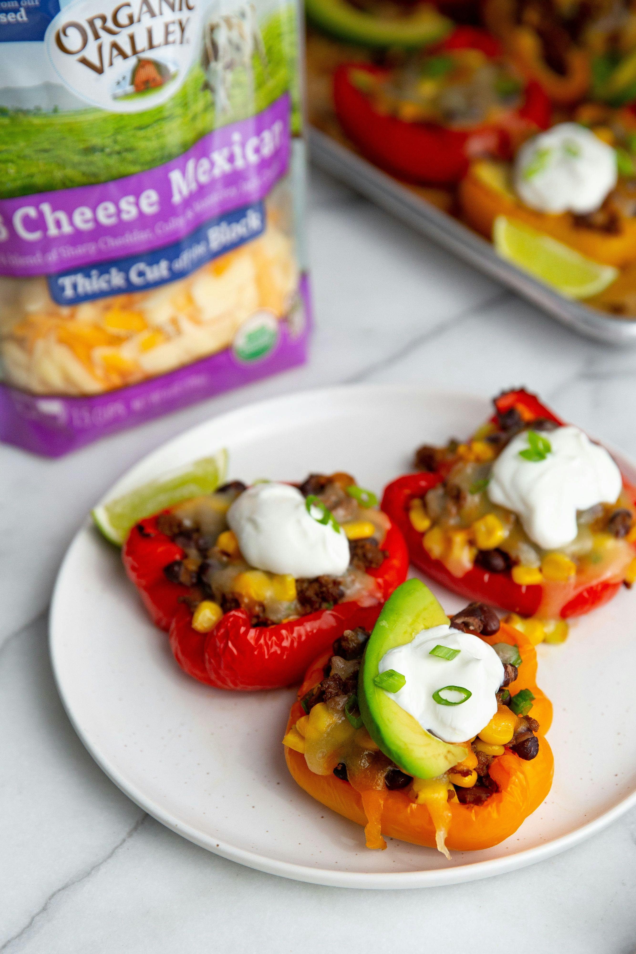 Cheesy stuffed peppers on a plate next to Organic Valley Shredded Cheese.