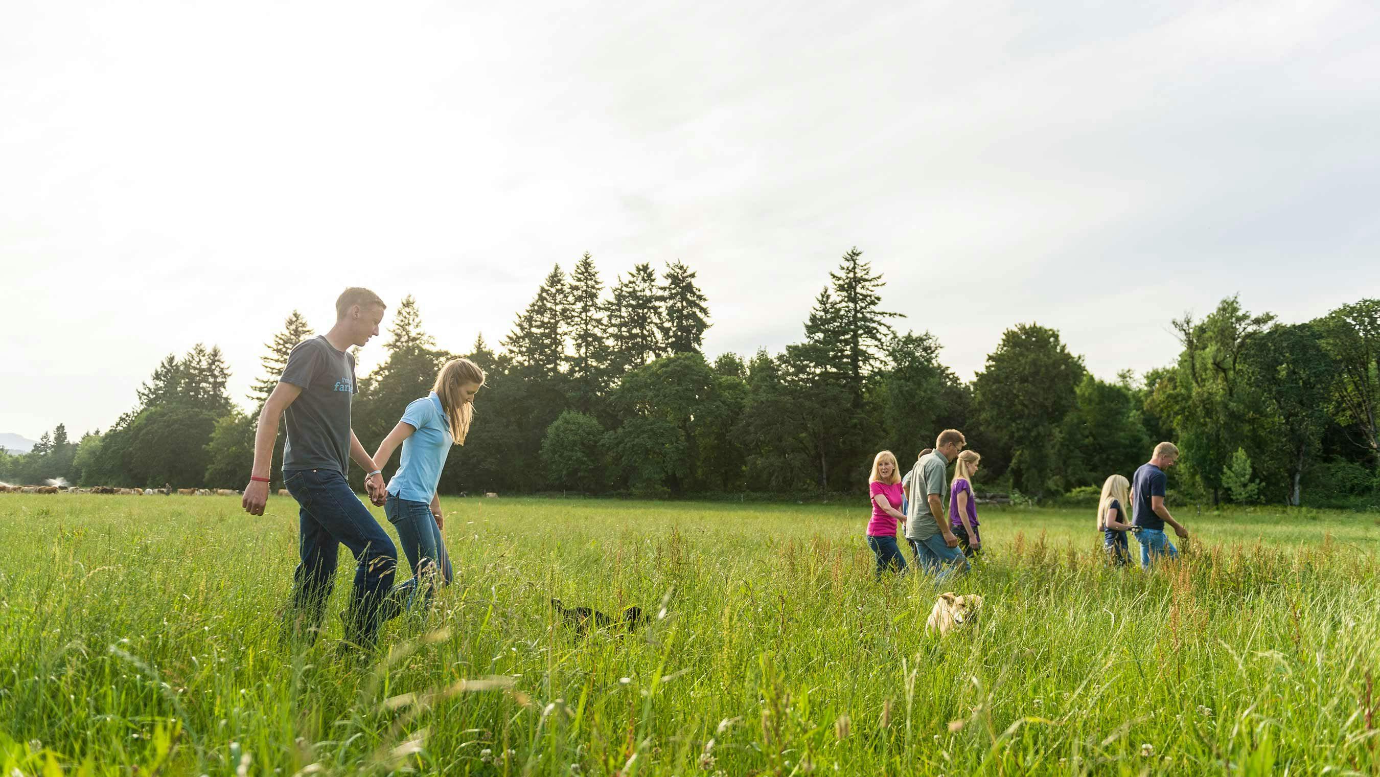 A farm family walking in the pasture grass.