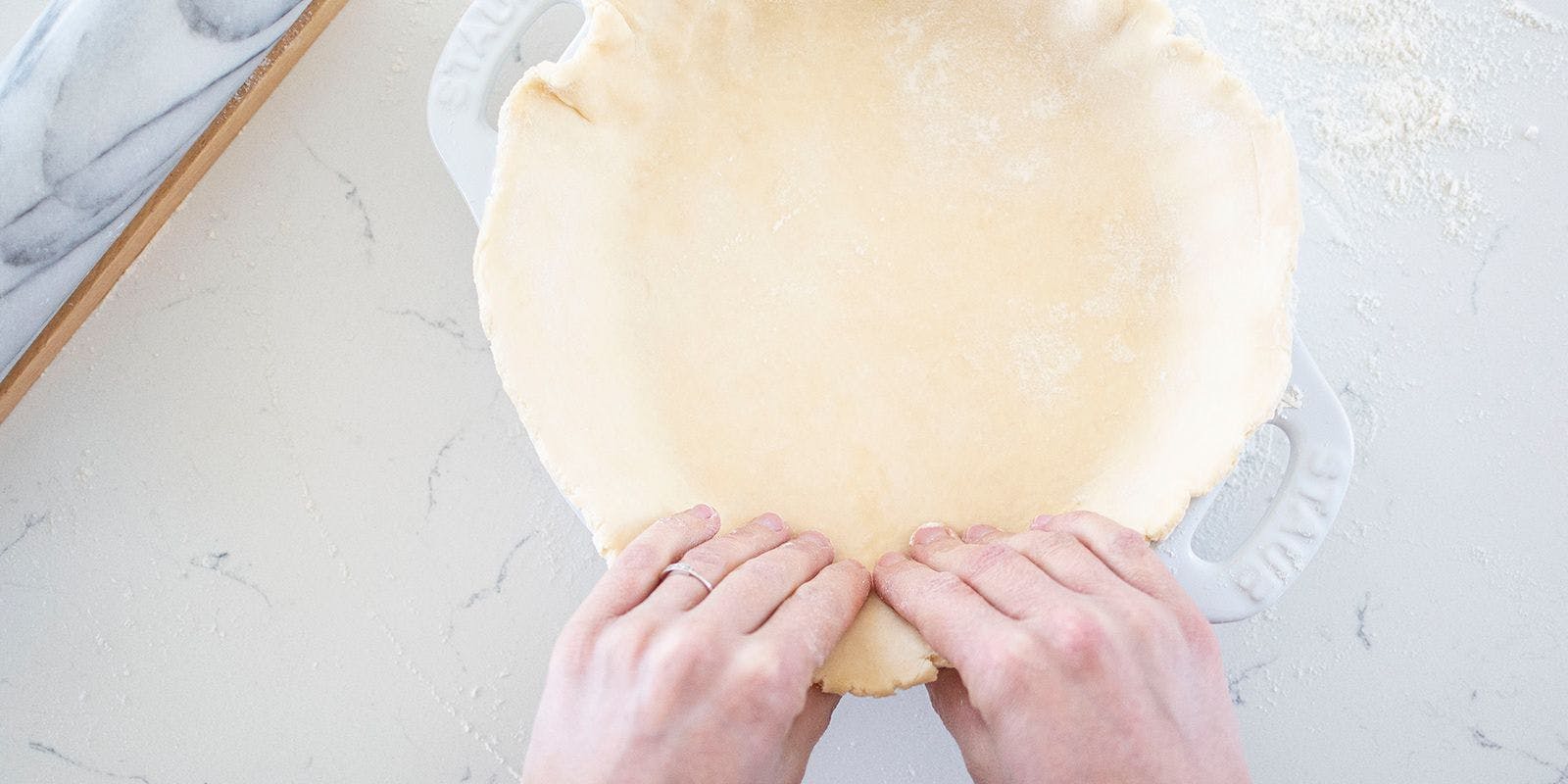 Hands shaping an all-butter pie crust into a pan. Mimi Council photo