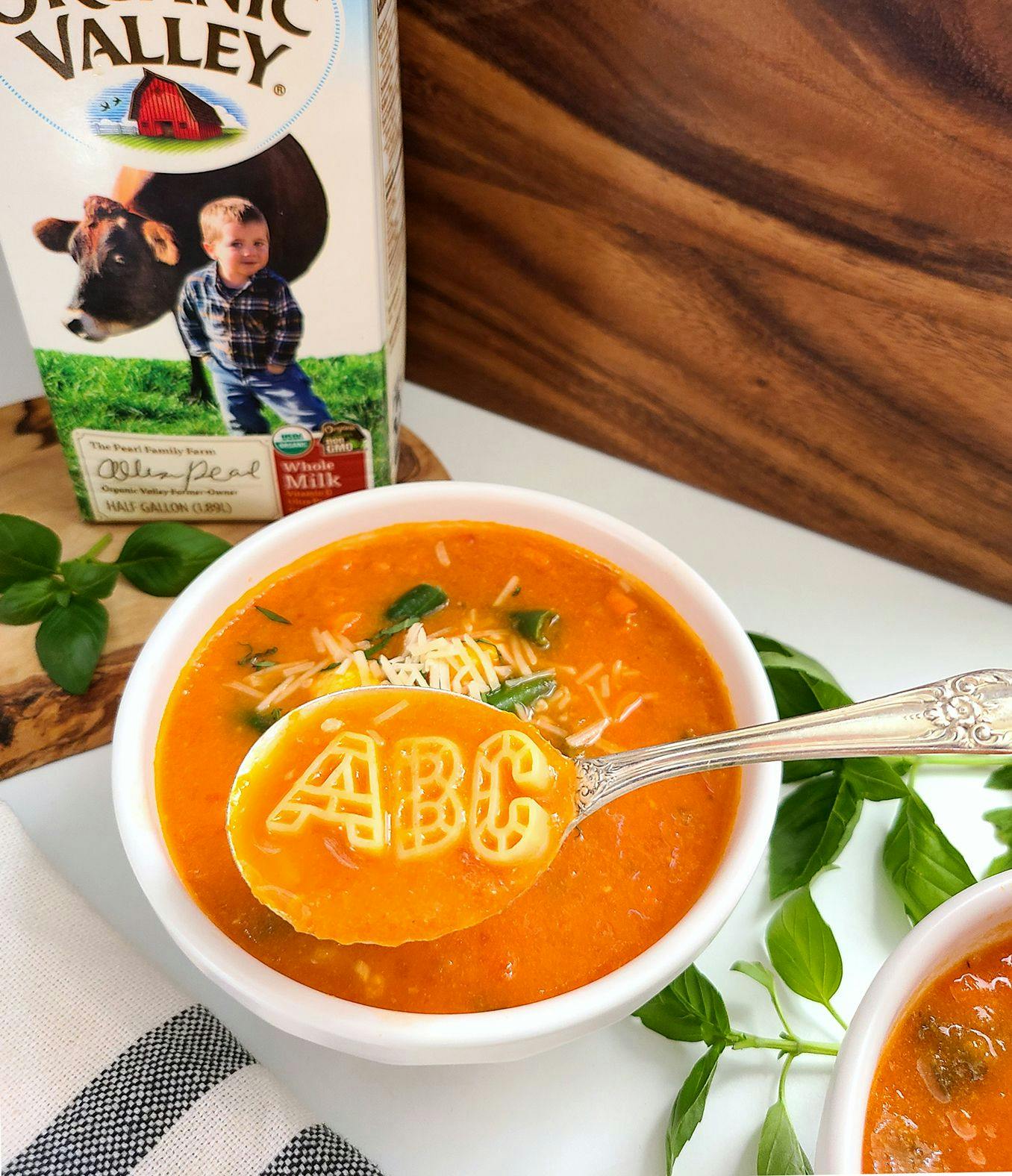 Tomato Soup with ABC noodles in it next to a carton of Organic Valley Whole Milk. 