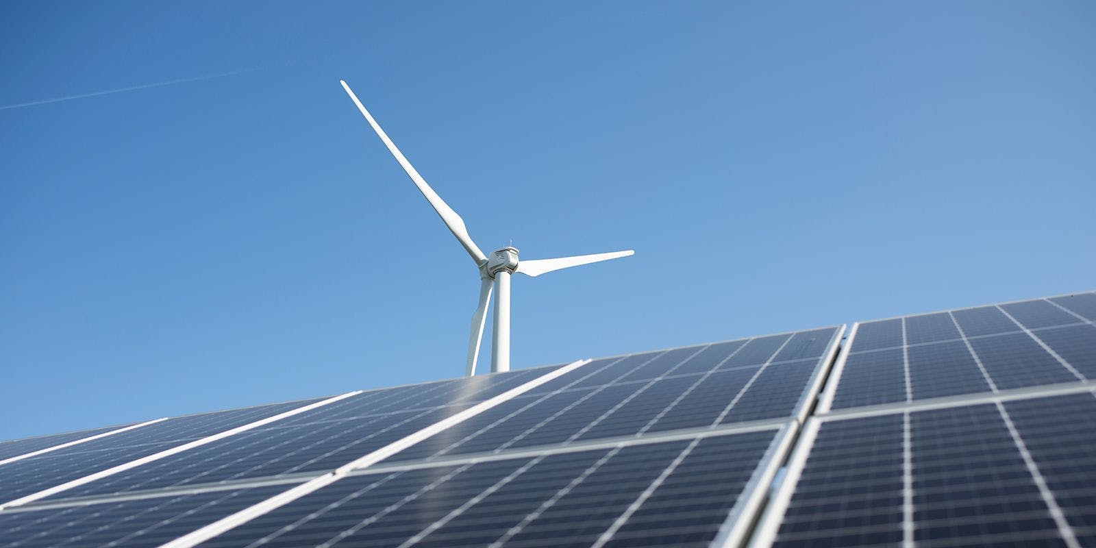 Solar panels and a wind turbine with a blue sky in the background.