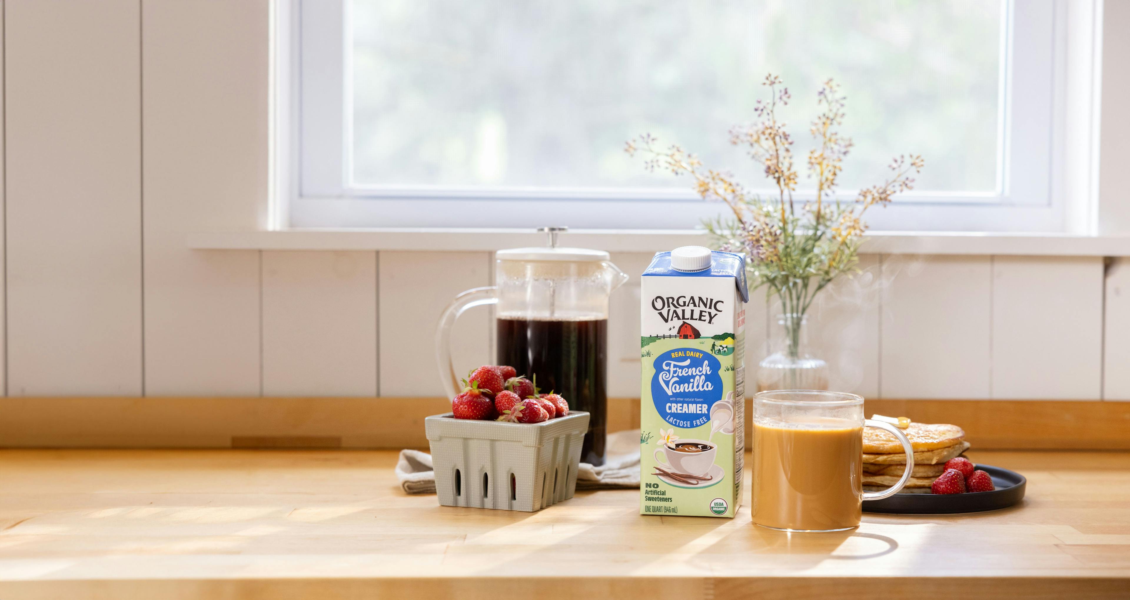 Flavored Creamer next to strawberries, coffee, and flowers. 